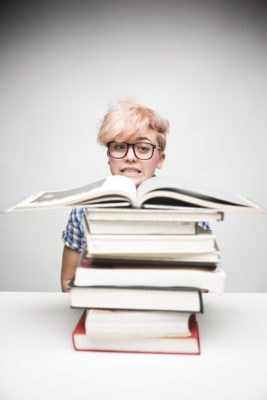 Worried Young Woman Sitting Behind Pile of Books