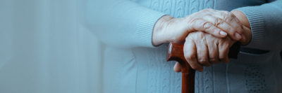 Close up of senior disabled woman's hands holding walking stick