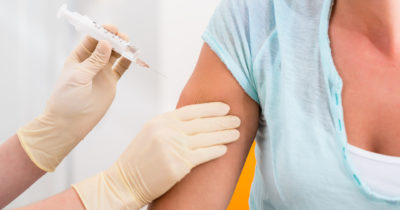 Woman at doctor getting vaccination syringe in arm